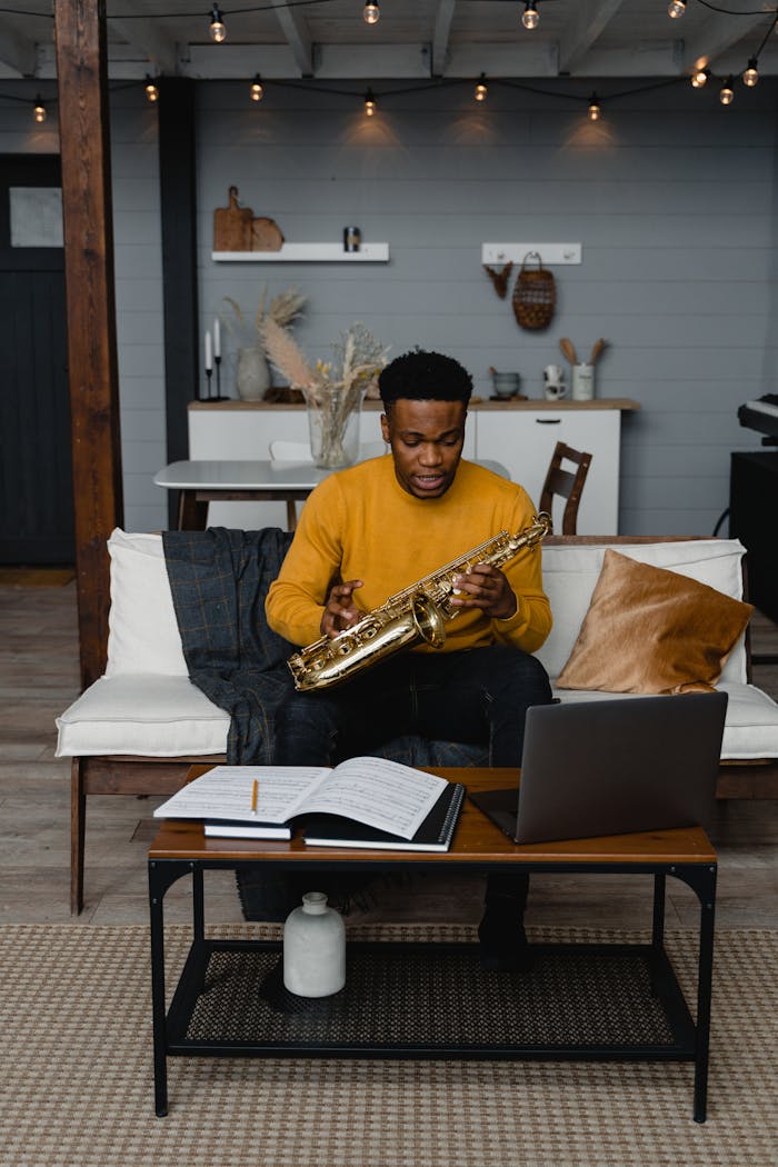A black musician practices the saxophone at home using online learning.